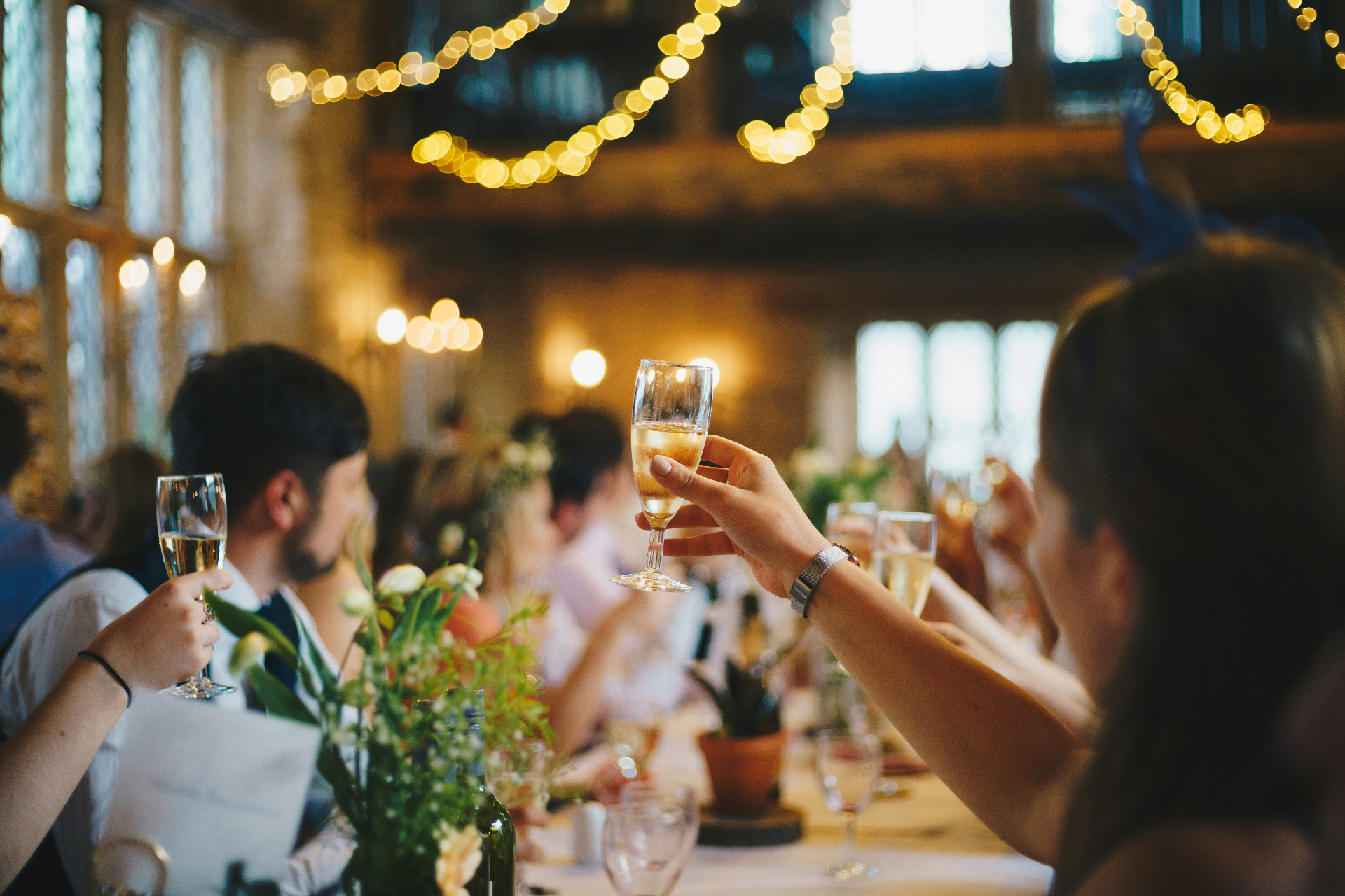 Wedding reception toast with champagne glasses and string lights